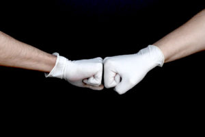 We're in this together image of two hands bumping fists and wearing gloves