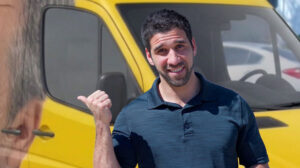 Smiling man giving thumbs up in front of yellow van